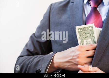 Business man hiding money in jacket pocket - Corruption and Fraud Concept Stock Photo