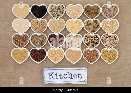Healthy grain food selection in heart shaped porcelain bowls with old metal kitchen sign forming an abstract background. Stock Photo