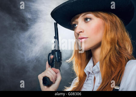 The beautiful girl in a hat, with a revolver. Stock Photo