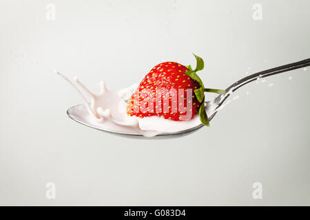 fresh strawberry splashing into spoon full of milk Stock Photo