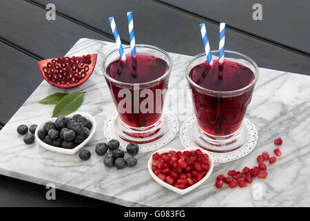 Blueberry and pomegranate juice drink with fresh fruit on marble over dark wood background. Stock Photo