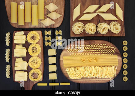 Abstract background of dried pasta selection on wooden maple boards over dark wood. Stock Photo