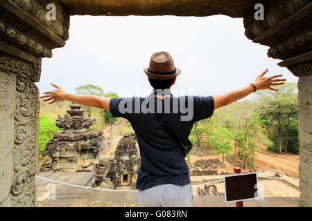 Young man spreading his hands in Angkor temples in Siem Reap, Cambodia. Stock Photo