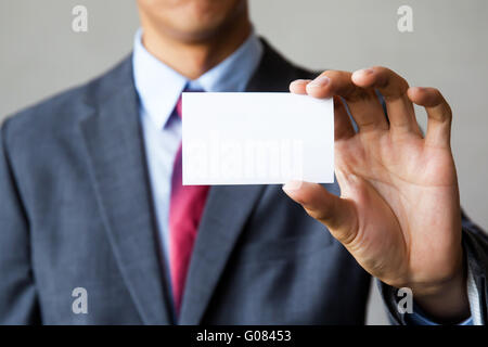 Young man in business suit holding white blank business card. Business name card presenting (mock up white card) Stock Photo