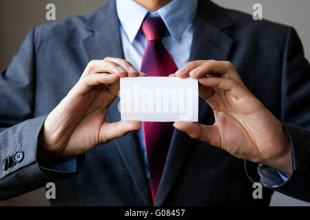 Young man in business suit holding white blank business card. Business name card presenting (mock up white card) Stock Photo