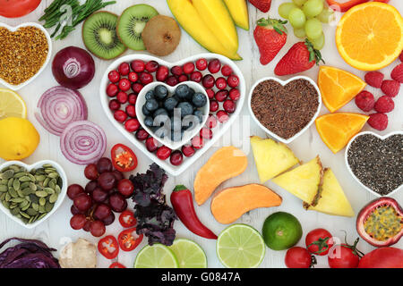 Paleo diet health and superfood of fruit, vegetables, nuts and seeds in heart shaped bowls on distressed white wood background, Stock Photo