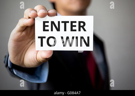 Businessman presenting 'Enter to Win' word on white card. Stock Photo