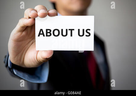 Businessman presenting 'ABOUT US' word on white card. Stock Photo