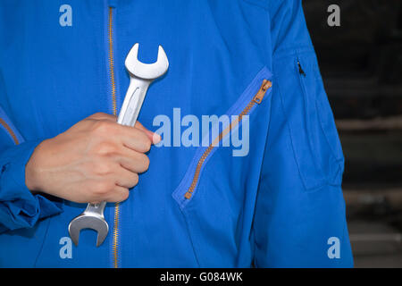 Man in blue technician uniform holding a wrench. Stock Photo
