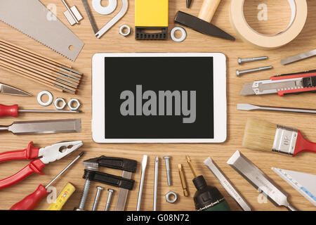 Digital touch screen banner with DIY and work tools all around on a wooden table, top view Stock Photo