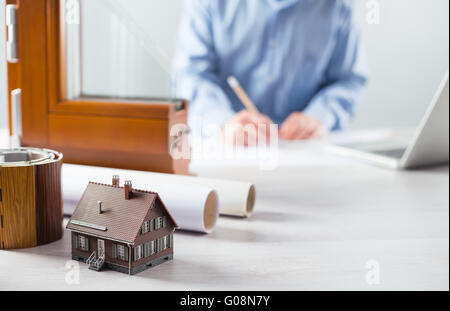 Windows section with triple glazing and wooden frame and man working on a house project with laptop on background Stock Photo