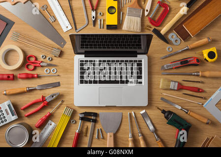 Laptop on a work table with DIY and construction tools all around, top view, hobby and crafts concept Stock Photo