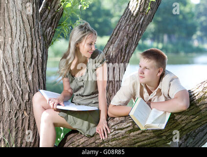 Young guy and girl with books on the nature near l Stock Photo