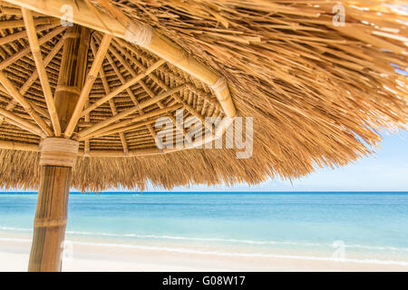 Straw umbrella on a beautiful tropical beach Stock Photo