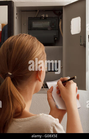 Young woman rewrites the electrical meter readings Stock Photo