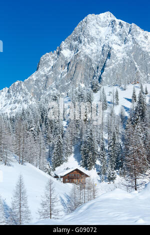 Winter rock with fresh fallen snow on top and house. Stock Photo