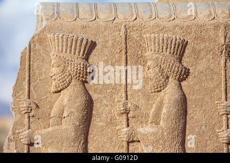 Soldiers of historical empire with weapon in hands. Stone bas-relief in ancient city Persepolis, Iran. Stock Photo