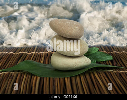 Stacked stones on wooden base for spa and green leafs Stock Photo