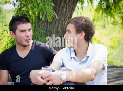 Two guys relaxing alongside a nature drink coffee Stock Photo
