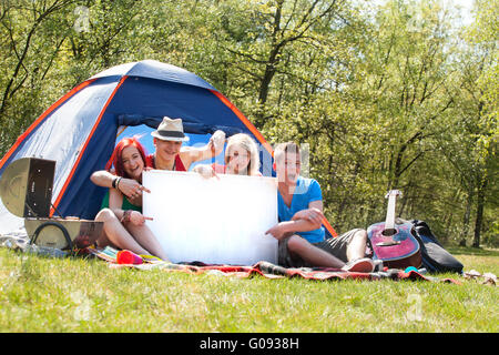 Teenagers on a camping with an empty sign board Stock Photo