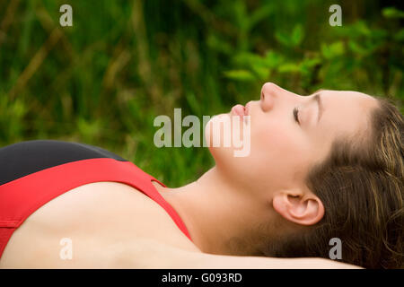 Sportive young adult resting in the grass of a meadow Stock Photo