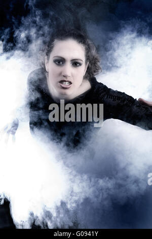 Woman with long curly hair crawling out of smoke Stock Photo
