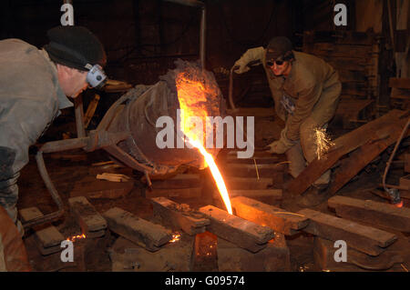 Foundry - molten metal poured from ladle into mould Stock Photo