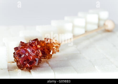 candy brown sugar on a stick lies on white lumpy s Stock Photo