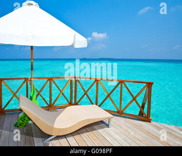 Parasol and chaise lounges on a terrace of water v Stock Photo