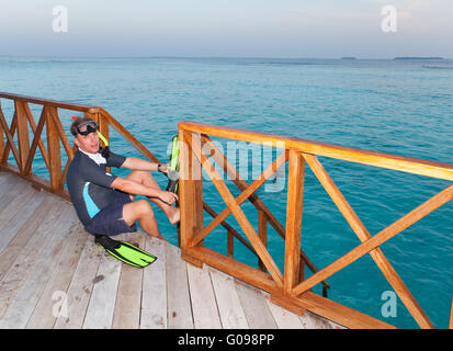 sporting man puts fins on foot before swim in the Stock Photo