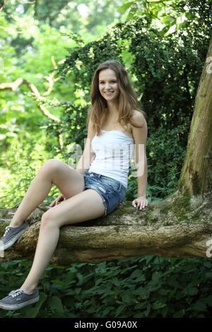 Pretty teenage girl sitting on a garden wall Stock Photo