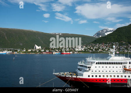 Norway, Tromso. Harbor area and waterfront view of the Arctic Cathedral. Hurtigruten ship, Nordlys, docked in Tromso. Stock Photo