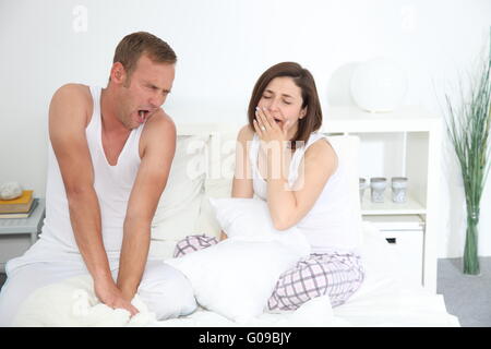 Middle-aged Caucasian sleepy couple yawning in bed Stock Photo