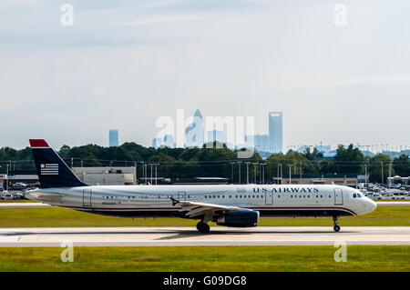 Commercial jet on an airport runway with city skyline in the background. Stock Photo