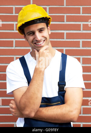 Friendly smiling worker in front of a brick wall Stock Photo