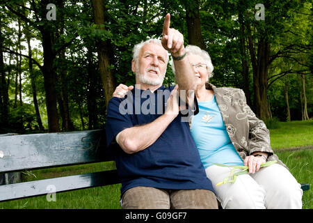 Couple sitting outside on a park bench Stock Photo