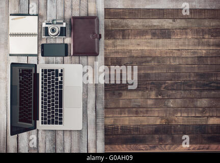 Grunge hipster wooden desktop with vintage camera, computer, mobile phone and notebook, blank copy space Stock Photo