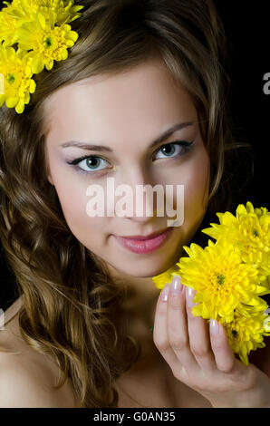 The girl with beautiful hair with yellow chrysanthemum Stock Photo