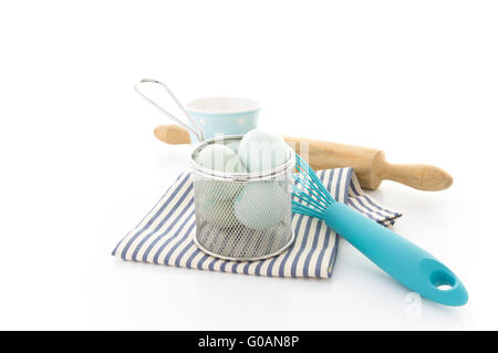 Pastry utensils with blue eggs, whisk and rolling pin on a white background with copyspace Stock Photo