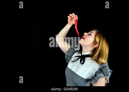 Blonde woman eating a red hot peppers Stock Photo