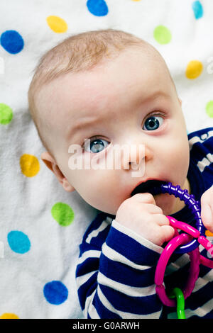 cute baby in striped clothes lying down on a blanket Stock Photo