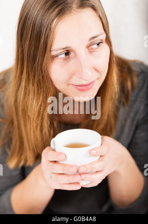 Happy girl in grey holding mug and not looking at camera Stock Photo