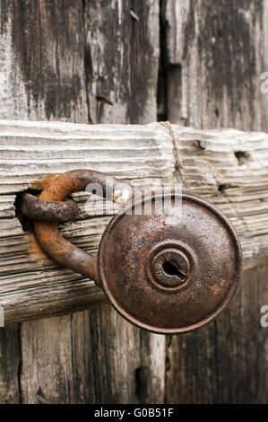 Old rusty padlock on weathered wooden door closeup Stock Photo