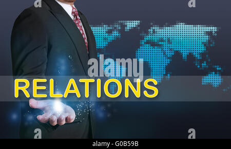 Business concept image of a businessman showing Relations word on his hand over blue background with dotted world map Stock Photo