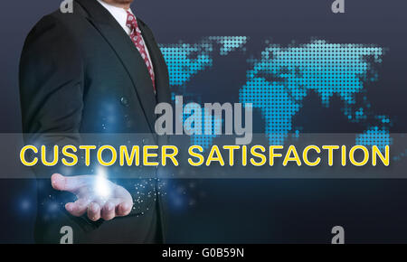 Business concept image of a businessman showing Customer Satisfaction words on his hand over blue background with dotted world m Stock Photo