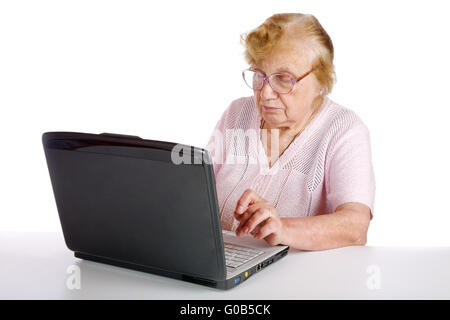 granny in glasses looks at the screen notebook on a white background Stock Photo