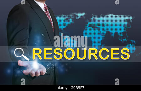 Business concept image of a businessman showing Resources word on his hand over blue background with dotted world map Stock Photo
