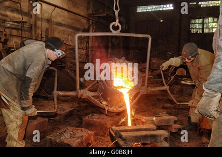 Foundry - molten metal poured from ladle into mould Stock Photo