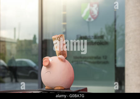A piggy bank stands with 50 euros before tax offic Stock Photo