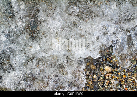 Small sea stones on the seashore, covered with a s Stock Photo
